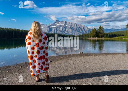 Une femme blonde, embusquées dans une couverture de citrouille, jouit d'une vue matinale sur le lac Two Jack, dans le parc national Banff Canada Banque D'Images