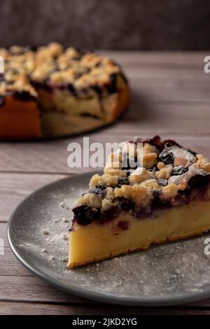 Morceau de gâteau aux myrtilles sur une table en bois avec de la poudre de sucre. Banque D'Images