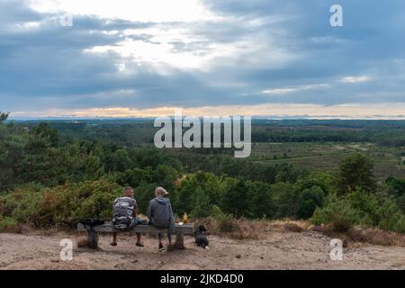 Stony Jump, un couple assis sur un banc au-dessus de ce point de vue en pierre à affûter, un affleurement rocheux sur Frensham Common, Surrey, Angleterre, Royaume-Uni Banque D'Images