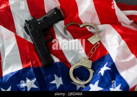 Arme à feu, étui et menottes devant le drapeau américain, à l'horizontale. Banque D'Images