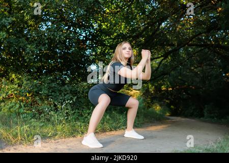 le modèle de fitness pour fille est utilisé pour les sports dans le parc faisant des squats Banque D'Images