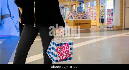Moscou, Russie, février 2021 : une cliente tient dans sa main des sacs en papier portant la marque Bath and Body Works dans un chèque bleu et blanc et un logo rose Banque D'Images