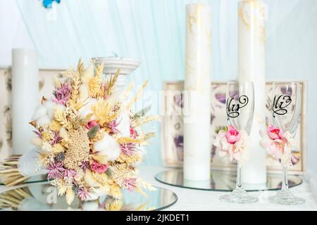 Arrangement de fleurs séchées pour un bouquet de mariée à côté de grandes bougies blanches Banque D'Images