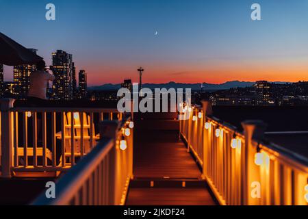 Homme prenant une photo téléphonique du coucher du soleil avec les gratte-ciel de Seattle depuis la terrasse sur le toit de Capitol Hill Banque D'Images