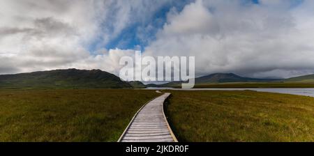 Un paysage panoramique de la piste côtière de Claggan Mountain tourbière et promenade avec la chaîne de montagnes Nephir en arrière-plan Banque D'Images