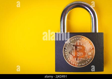 La crypto-monnaie est interdite. Interdiction du transfert du bitcoin. Baisse de débit. Pièce de monnaie Bitcoin et cadenas sur fond jaune. Banque D'Images