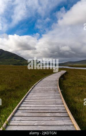 Une vue verticale de la piste côtière de Claggan Mountain et de la promenade avec la chaîne de montagnes Nephir en arrière-plan Banque D'Images