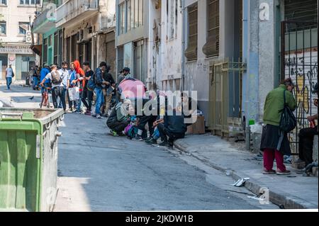 ATHÈNES, GRÈCE - 14 MAI 2022 : un homme sans domicile dort sur un trottoir dans le centre-ville d'Athènes. Les touristes passent. Banque D'Images