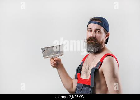 Générateur avec spatule. Portrait d'un homme barbu en combinaison et d'une casquette de baseball. Banque D'Images