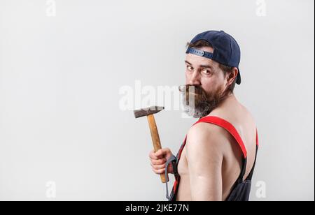 Portrait d'un homme barbu dans une casquette de baseball avec un marteau dans la main. Copiez l'espace pour votre texte. Banque D'Images