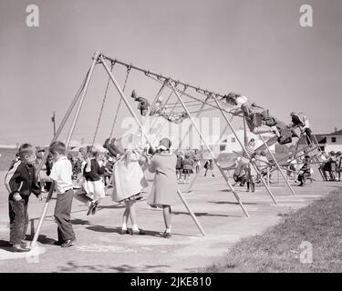 1950S SUBURBAIN ÉCOLE TERRAIN DE JEU BONDÉ AVEC DES GARÇONS ET DES FILLES SUR DES BALANÇOIRES - J3940 HAR001 HARS PRIMAIRE BALANÇOIRE COOPÉRATION AIR FRAIS CLASSE ÉCOLE TOGETHERNESS NOIR ET BLANC CAUCASIEN ETHNICITÉ HAR001 VIEUX MODE Banque D'Images