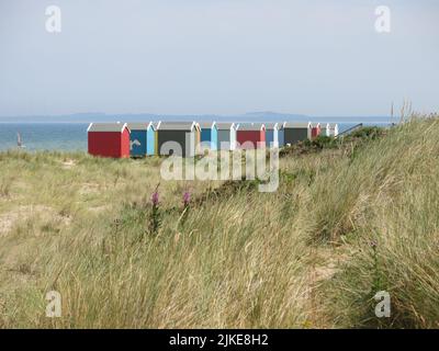 Une rangée de cabanes de plage colorées sur le rivage à Findhorn, l'un des joyaux cachés de la côte de ne Moray en Écosse. Banque D'Images