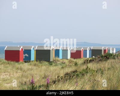 Une rangée de cabanes de plage colorées sur le rivage à Findhorn, l'un des joyaux cachés de la côte de ne Moray en Écosse. Banque D'Images