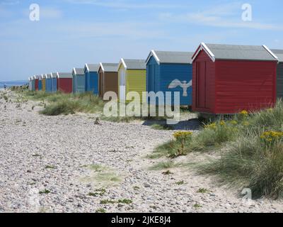 Une rangée de cabanes de plage colorées sur le rivage à Findhorn, l'un des joyaux cachés de la côte de ne Moray en Écosse. Banque D'Images