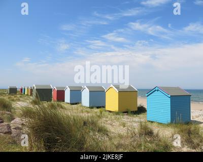 Une rangée de cabanes de plage colorées sur le rivage à Findhorn, l'un des joyaux cachés de la côte de ne Moray en Écosse. Banque D'Images