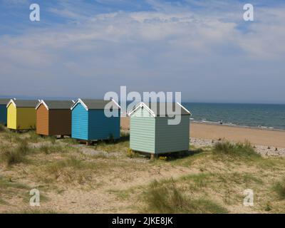 Une rangée de cabanes de plage colorées se dresse au milieu des dunes de sable sur la belle plage de sable de Findhorn - une destination balnéaire sur la côte écossaise de Moray. Banque D'Images