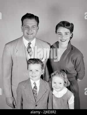 1950S PORTRAIT DE LA FAMILLE DE 4 MÈRE PÈRE DEUX ENFANTS UN GARÇON ET UNE FILLE SOURIANT REGARDANT L'APPAREIL PHOTO - J950 HAR001 HARS 4 MÈRES VIEUX TEMPS NOSTALGIE FRÈRE VIEILLE MODE SOEUR 1 ENFANT STYLE FILS HEUREUX FAMILLES JOIE STYLE DE VIE SATISFACTION FEMMES FRÈRES MARIÉS STUDIO SHOT CONJOINT ÉPOUX SANTÉ VIE VIE COPIE ESPACE AMITIÉ DEMI-LONGUEUR FEMMES FILLES PERSONNES HOMMES FRÈRES ET SŒURS CONFIDENCE SŒURS PÈRES B&W PARTENAIRE CONTACT VISUEL COMBINAISON ET CRAVATE BONHEUR JOYEUX GRAND ANGLE ET ENTHOUSIASME DADS FIERTÉ FRÈRES SOURIRES CONNEXION JOYEUSE CROISSANCE ÉLÉGANTE JEUNES MI-ADULTES MI-ADULTES HOMME Banque D'Images