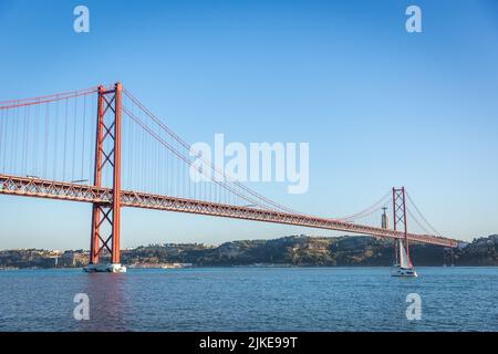 Lisbonne, Portugal - 2018, 14 mai - petit bateau en direction de la version portugaise du Golden Gate de Lisbonne Banque D'Images