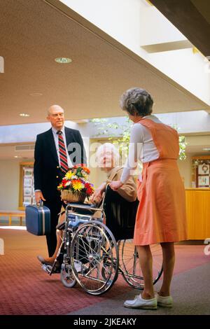 1980S FEMME VOLONTAIRE AIDE À L'HÔPITAL AVEC UNE FEMME SÉNIOR EN FAUTEUIL ROULANT ET UN HOMME SON MARI ATTENDANT SON SAC DE TRANSPORT - KM9431 NET002 HARS VIEUX TEMPS NOSTALGIE INFIRMIÈRES VIEILLE MODE 1 AIDE INFIRMIÈRE JOIE HEUREUSE STYLE DE VIE FEMMES AÎNÉES CONJOINT MARIÉ ÉPOUX ESPACE DE COPIE DE MALADIE PLEINE LONGUEUR DEMI-LONGUEUR FEMMES PERSONNES HOMMES HOMME SENIOR HOMME PARTENAIRE ADULTE SENIOR FEMME SOINS DE SANTÉ COSTUME ET CRAVATE PROFESSION VIEILLESSE OLDSTERS FOURNISSEUR DE PRÉVENTION GAIE FOURNISSEURS OLDSTER PRATICIENS GUÉRISON ET DIAGNOSTIC RÉTABLISSEMENT DE BAS ANGLE PROFESSIONS DE SOINS DE SANTÉ SOURIRES TRAITEMENT ANCIENS GUÉRISSEURS HÔPITAUX Banque D'Images