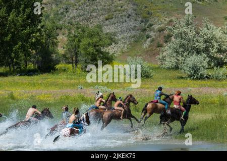 Les braves indiennes américaines font la course à la guerre à cheval en traversant la rivière Little Bighorn pendant la reconstitution annuelle du dernier stand de Custer, Montana Banque D'Images