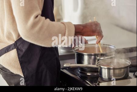 La cuisine est l'endroit où il fait son meilleur travail. Un homme méconnaissable cuisant sur son poêle dans la cuisine à la maison. Banque D'Images