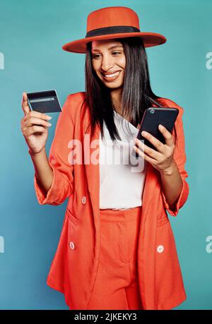 Une femme heureuse et excitée magasiner en ligne, acheter avec une carte de crédit ou payer des factures par téléphone. Isolé gaie dame faisant un achat sur un site Web Banque D'Images