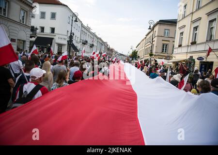 Varsovie, Pologne. 01st août 2022. Une foule de gens est vue marcher avec un énorme drapeau polonais pour commémorer le 78th anniversaire du soulèvement de Varsovie. Des milliers de personnes ont participé à une marche organisée par les organisations nationalistes pour célébrer le 75th anniversaire du soulèvement de Varsovie. Le soulèvement de Varsovie (Powstanie Warszawskie) a été la plus grande opération militaire par tout mouvement de résistance en Europe contre les occupants allemands nazis pendant la Seconde Guerre mondiale Crédit : SOPA Images Limited/Alamy Live News Banque D'Images