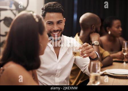 Nous ne sommes jamais à court de choses à dire. Un beau jeune homme assis et appréciant un dîner du nouvel an avec des amis. Banque D'Images