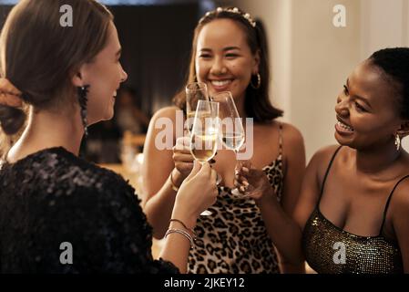 Que le nouvel an nous apporte beaucoup d'aventures. Un groupe varié d'amis debout et toaster avec du champagne lors d'un dîner du nouvel an Banque D'Images