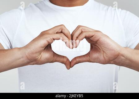 Mettez un peu de coeur dans lui. Un homme méconnaissable formant une forme de coeur avec ses mains. Banque D'Images