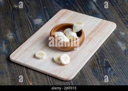 tranché de banane mûre sur une planche en bois, cuisant de la banane trantée en tranches Banque D'Images