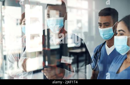 Partage des connaissances. Un groupe de médecins discutant des formules au bureau au travail a été photographié. Banque D'Images