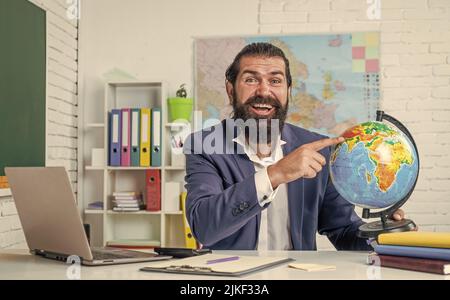 Professeur de sexe masculin dans la salle de classe enseignant la géographie pointant vers une carte du monde, l'éducation Banque D'Images