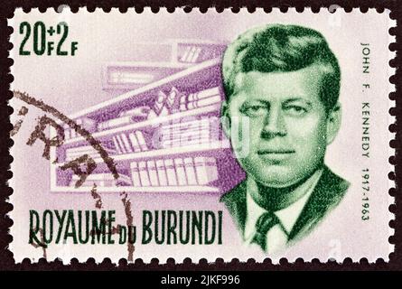 BURUNDI - VERS 1966 : un timbre imprimé au Burundi montre le Président Kennedy et la bibliothèque commémorative, vers 1966. Banque D'Images