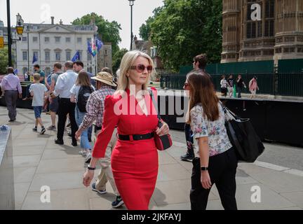 Liz Truss, alors secrétaire en chef du Trésor, marche non reconnue à Westminster dans une robe rouge et des chaussures avec des lunettes de soleil rouges assorties Banque D'Images