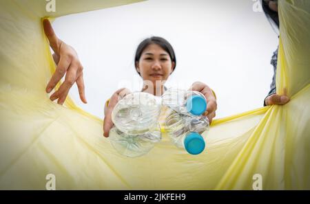 Une femme jette les déchets plastiques dans un poubelle. Femme mettant la bouteille de plastique poubelle dans les ordures Banque D'Images