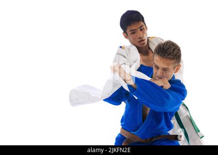 Portrait dynamique de deux jeunes hommes, entraînement professionnel des athlètes judo, combat isolé sur fond blanc Banque D'Images