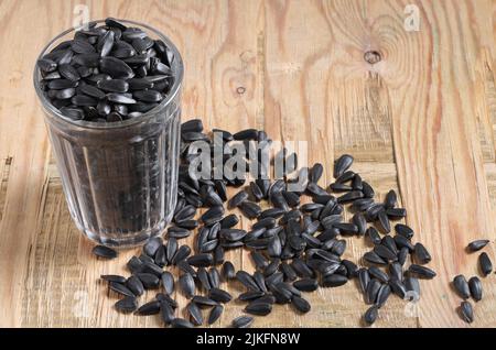 Verre aux graines de tournesol noires sur un vieux fond en bois Banque D'Images