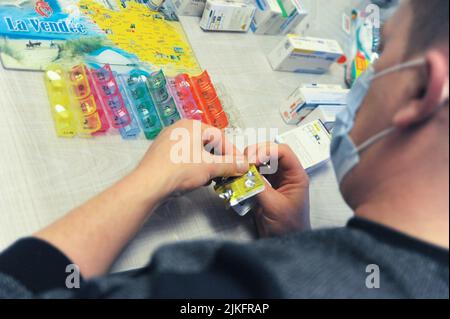 Une infirmière privée prépare une boîte à pilules au domicile d'un patient. Banque D'Images