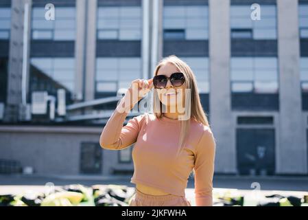 Portrait d'une femme souriante heureuse portant des lunettes de soleil en ville en été Banque D'Images