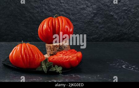Un groupe de grosses tomates Costoluto avec origan sur fond gris, espace pour le texte Banque D'Images