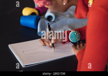 Une jeune femme de mode afro-américaine dessine des croquis au bureau du studio Banque D'Images