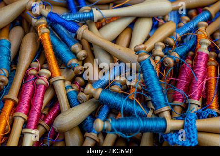 Dentelle bobinale. Fils de dentelle bleu, orange et violet. Gros plan sur les fils colorés. Détails. Banque D'Images