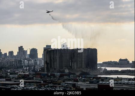 Beyrouth, Liban, le 31 juillet 2022. Les hélicoptères aquatiques sont à l'abri de la ruine qui couve des silos à céréales du port de Beyrouth. Le grain en fermentation a pris feu et a brûlé pendant plus de deux semaines à l'intérieur des silos, fortement endommagé il y a deux ans dans l'explosion du port de Beyrouth, le 4 août 2020, avant que deux silos du bloc nord de la structure instable ne s'effondrent. Banque D'Images