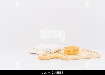 gâteau de carottes bio dans une tasse en papier avec farine d'épeautre, serviette de cuisine et planche à découper en bois sur une table blanche Banque D'Images