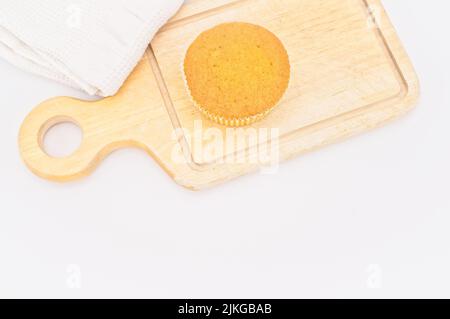 gâteau de carottes bio dans une tasse en papier avec farine d'épeautre, serviette de cuisine et planche à découper en bois sur une table blanche Banque D'Images