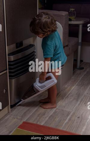 Mignon et diligent bébé nettoie la caravane avec un aspirateur. Banque D'Images