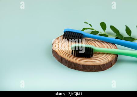 Brosses à dents et feuilles multicolores sur fond vert. Concept de produits cosmétiques pour les soins dentaires. Flat lay, vue de dessus, espace de copie Banque D'Images