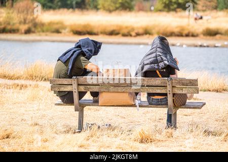 Wimbledon , Londres, Royaume-Uni 2 août 2022. Les gens qui se détendent sur l'herbe parchée avec leur tête couverte sur Wimbledon Common lors d'une journée chaude et humide alors que le temps chaud est prévu pour revenir avec les températures élevées exeding 30celsiusCredit. amer ghazzal / Alay Live News Banque D'Images