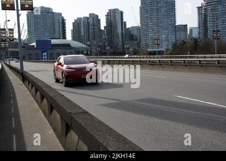 Une voiture rouge Volks Wagen passant par l'aqueduc de Géorgie de l'Ouest avec une vue sur la ville en arrière-plan Banque D'Images